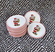 a stack of christmas plates with santa clause on them sitting on a black and white table cloth