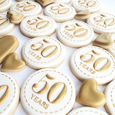 white and gold decorated cookies with the number 50 on them, all in different shapes