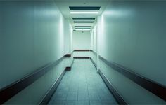 an empty hallway with white walls and tile flooring