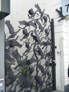 a large metal gate with birds on it's sides and an open door to the outside