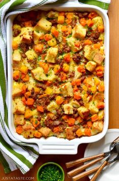 a casserole dish with carrots and meat in it on a wooden table