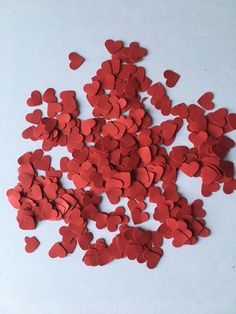 red hearts are scattered on a white surface for use as confetti or decorations