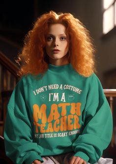 a woman with red hair wearing a green sweatshirt that says i don't need a costume, i'm a math teacher