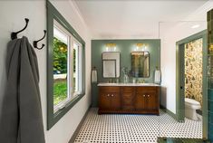 a bathroom with green walls and tile flooring next to a large mirror on the wall