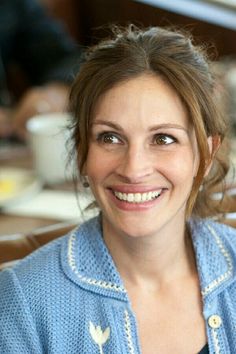 a smiling woman sitting at a table with food in front of her