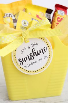 a yellow bucket filled with lots of candy and some stickers on the top that says, just a little sunshine to brighten your day