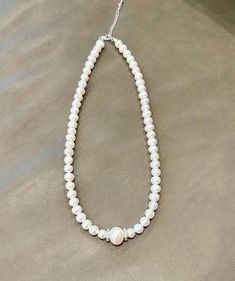 This stunning freshwater pearl necklace embodies timeless elegance and sophistication. Each genuine freshwater pearl is carefully selected for its beautiful luster, making this necklace the perfect accessory to add a touch of class to any outfit. The pearls are strung on a durable yet delicate thread, ensuring longevity without compromising on beauty. *Length: The necklace measures 18.25 inches. *Materials: The clasp and findings are made of 925 sterling silver. *Pearl Size: The main pearls measure 7-7.5 mm, with a 12 mm accent pearl that is both clean and rustic. Experience the quality of these high-grade white pearls! Care Instructions 1. Pearls: *To maintain their luster, gently wipe your pearls with a soft cloth before storing them. *Store them separately from other jewelry in a soft c Classic Pearl White Beaded Necklace With Pearl Drop, Pearl Charm Bridal Necklace With Round Beads, Pearl White Necklace With Pearl Charm, Bridal Necklace With Round Pearl Beads And Charm, Pearl White Necklace With Pearl Drop, Pearl Necklace With Round Beads And Pearl Charm, Pearl Necklace With Round Beads, Single Strand Pearl Bridal Necklace With Round Beads, Pearl Bridal Necklace With Single Strand Of Round Beads