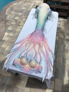 an image of a mermaid tail on a beach towel next to a swimming pool with sand in it