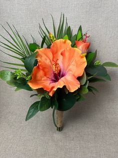 an orange flower bouquet with green leaves on a gray background in front of a white wall