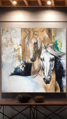 two horses are standing next to each other in front of a painting on the wall