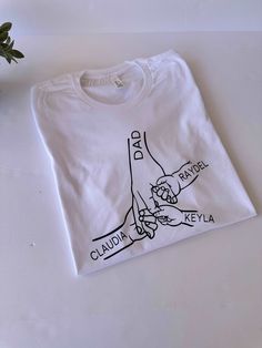 a white t - shirt with a drawing of two hands holding each other