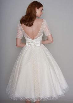 the back of a woman's white dress with polka dots and a bow at the waist