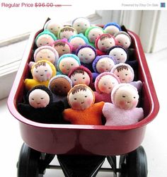 a wheelbarrow filled with small dolls sitting on top of a white floor next to a window