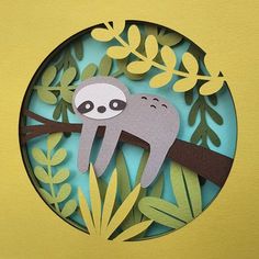 a paper cut out of a slotty sitting on a tree branch with leaves around it