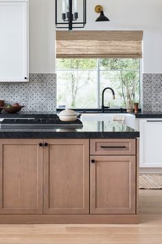 a kitchen with white cabinets and black counter tops, along with an island in the middle