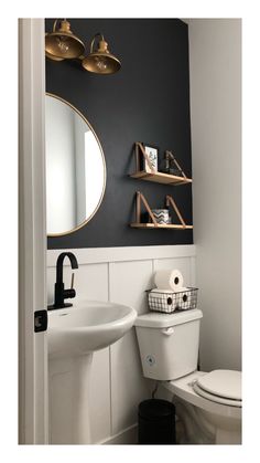 a white toilet sitting next to a bathroom sink under a mirror and gold accents on the wall