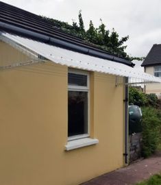 a yellow house with a black roof and white trim