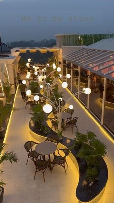 an outdoor dining area with tables, chairs and lights on the roof terrace at night