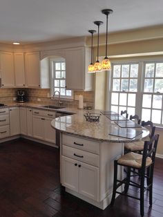 a kitchen with white cabinets and wooden floors