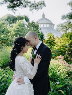 a bride and groom standing together in the garden