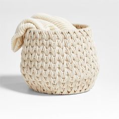 a white woven basket with a knot on the top and bottom, sitting in front of a white background