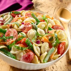 a white bowl filled with pasta salad on top of a wooden table