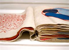 a stack of folded papers sitting on top of a white tablecloth covered in red and blue designs