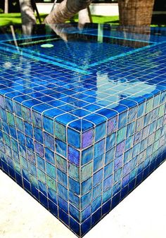 a blue tiled table sitting on top of a cement ground next to a palm tree