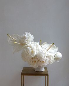 a vase with white flowers on a small table