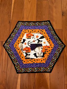 an orange, purple and black patchwork table topper with halloween cats on it