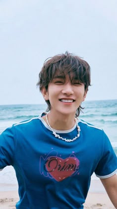 a young man standing on top of a beach next to the ocean