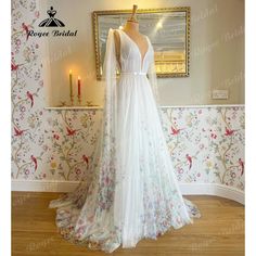 a white wedding dress on display in front of a wallpapered room with candles