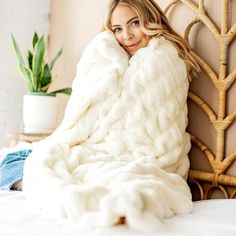 a woman laying on top of a bed under a blanket