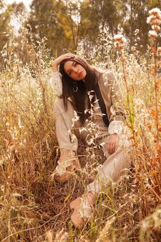 a woman is sitting in the tall grass