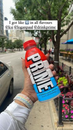 a person holding up a bottle of protein drink in front of a car on the street