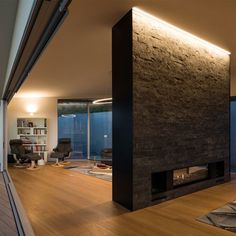 a modern living room with wood flooring and black stone fireplace in the middle of it