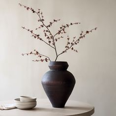 a vase sitting on top of a table next to a plate and bowl with flowers in it