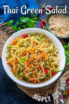 a white bowl filled with noodles and vegetables next to some silverware on a table