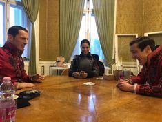 three people sitting at a table talking to each other