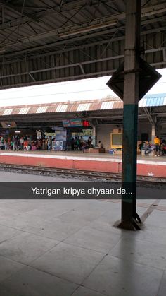 an empty train station with people waiting for the train to arrive at it's stop