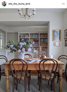 a dining room table with chairs and vases on it's centerpiece in front of bookshelves