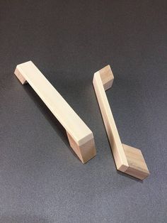 two pieces of wood sitting next to each other on a gray surface with one piece missing