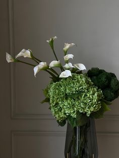 a vase filled with white flowers and green foliage