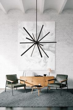 a dining room table and chairs in front of a white brick wall with a large clock hanging above it