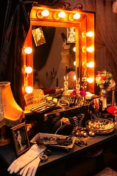 a vanity with makeup and accessories on it in front of a mirror that is lit up