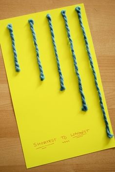 four green stringed objects are on top of a yellow piece of paper