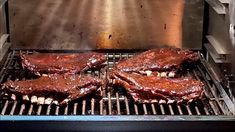 three ribs cooking on the grill in an outdoor oven with light coming from behind them