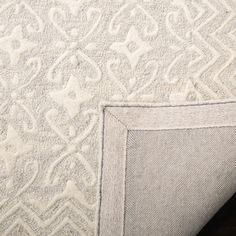 the corner of a white rug with an intricate design on it's edges and bottom