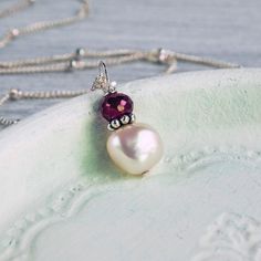 "This pendant features a perfectly imperfect freshwater pearl, beautifully smooth and shiny, offset with a deep red ruby. It is a classic and simple dainty style appropriate for any occasion yet just unusual enough to show that you dance to the beat of a different drum. I have accented the pearl and ruby with a tiny sterling silver \"daisy\", giving the pendant all the more textural interest. I offer 3 different styles of sterling silver chain finished with a sterling silver spring ring clasp. S Ruby And Pearl, Dainty Style, Necklace Layering, Ruby Necklace, June Birthstone, July Birthstone, Layering Necklace, Silver Spring, Red Ruby