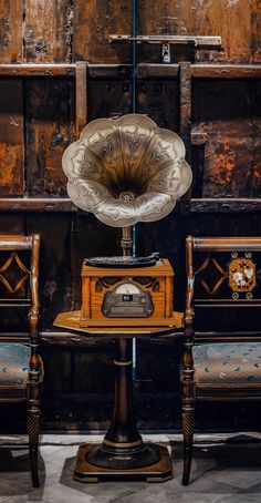 an old fashioned radio sitting on top of a wooden table next to two chairs and a trunk